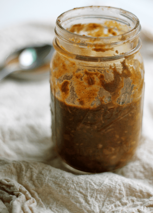 Horizontal view of a small mason jar filled with a thick dark orange oat mixture.
