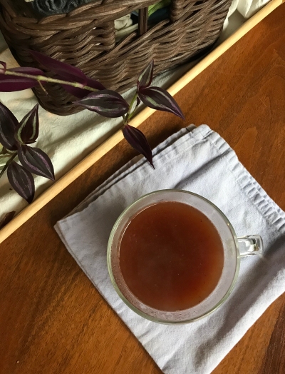 Top-down image of cacao tea in a glass mug.